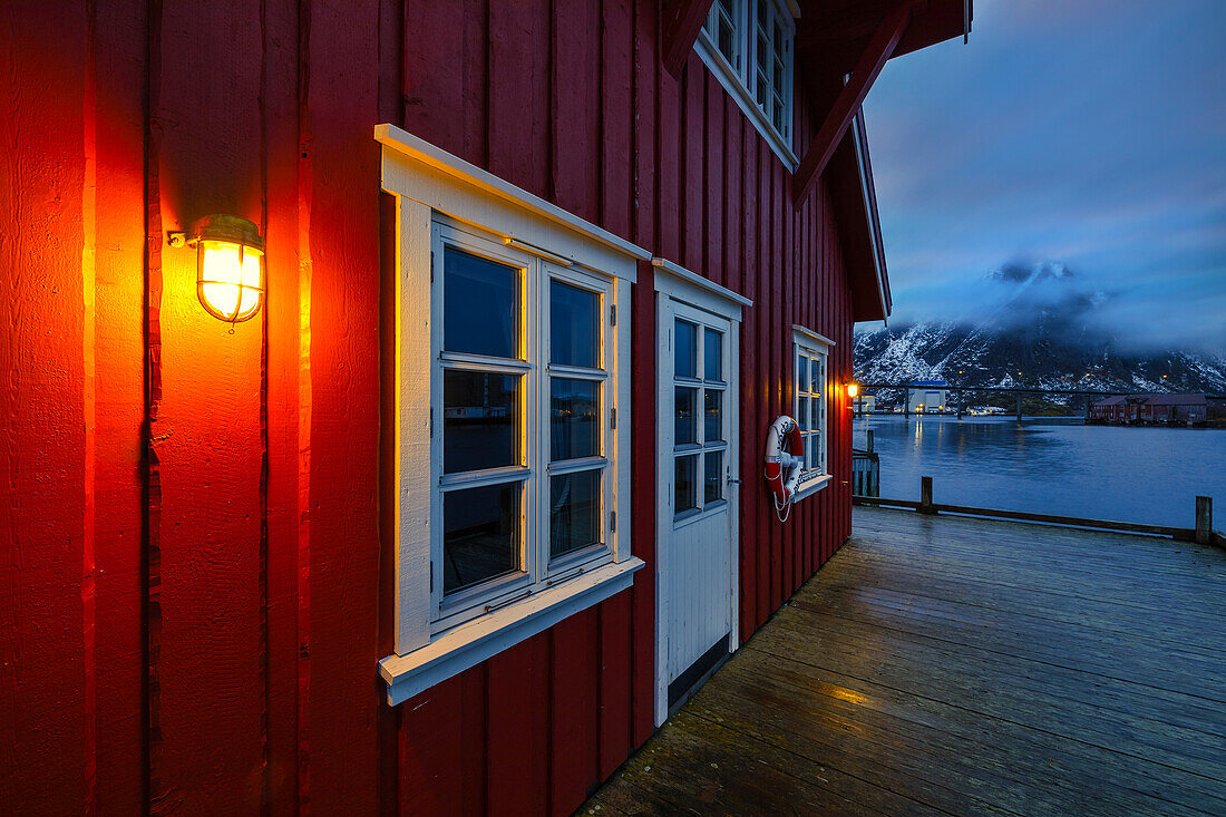 Rot beleuchtete Hütte in der Abenddämmerung in Svolvaer, Vagan, Austagoy, Nordland, Lofoten, Norwegen, Nordeuropa