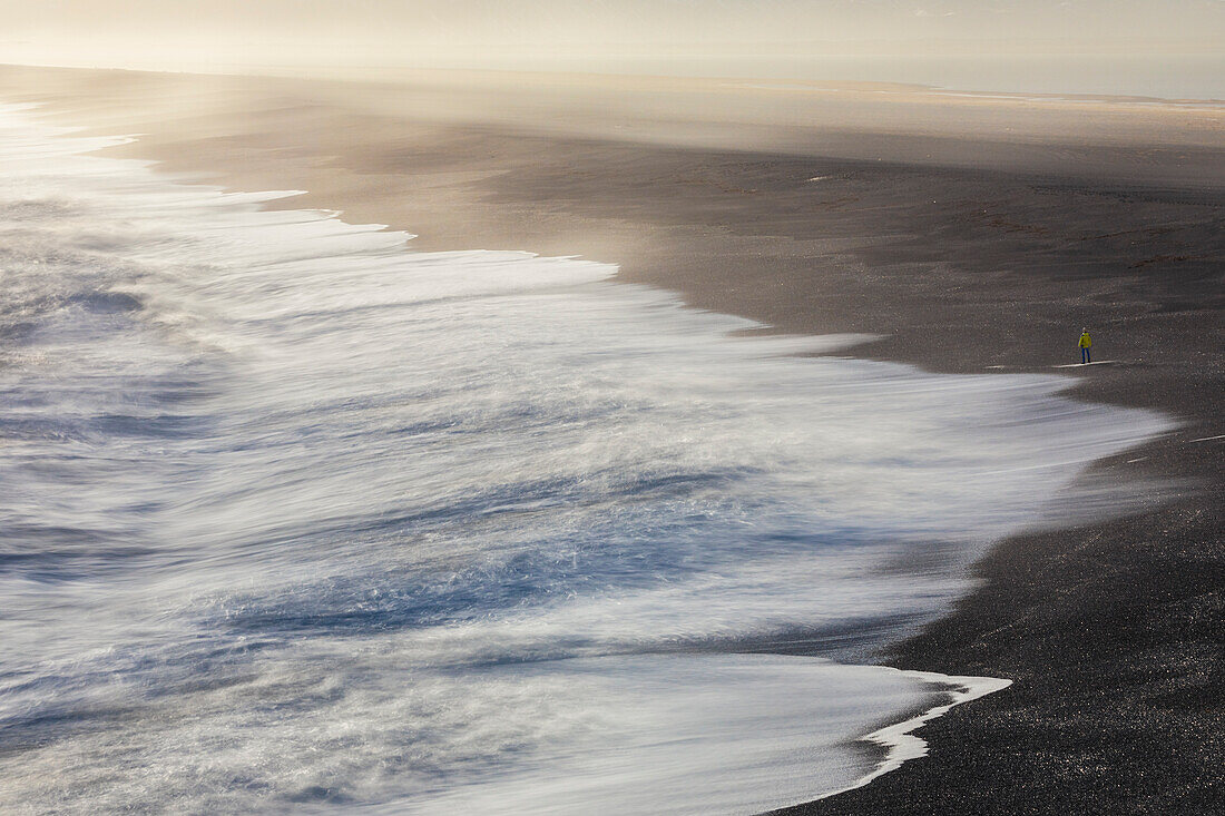 Ein Mann spaziert am isländischen Strand in der Nähe von Eystrahorn bei Sonnenuntergang, Krossanesfjall, Djupivogur, Austurland, Island, Nordeuropa