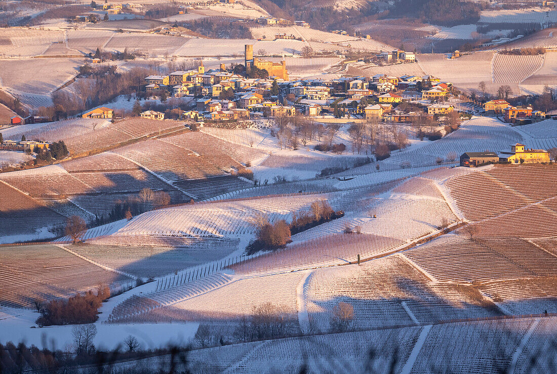 Blick auf die Stadt und die Burg von Castiglione Falletto von La Morra aus bei Sonnenuntergang im Winter. Langhe, Bezirk Cuneo, Piemont, Italien.