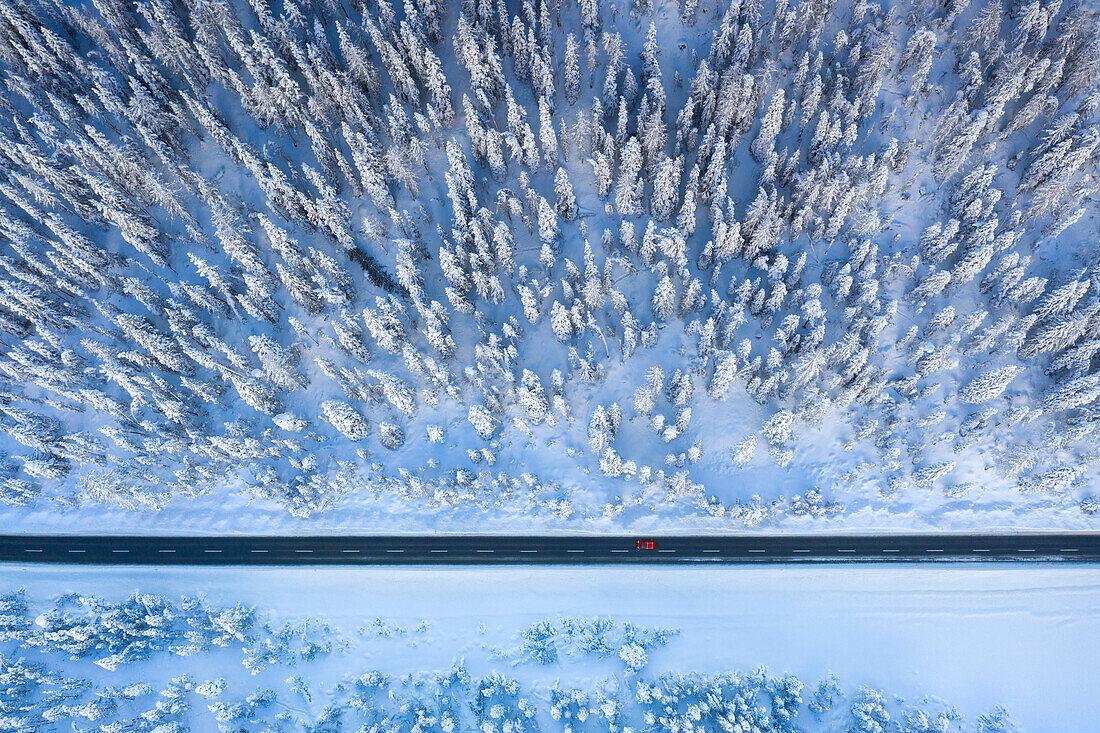Luftaufnahme eines Autos, das auf einer winterlichen Bergstraße fährt, Graubünden, Engadin, Schweiz