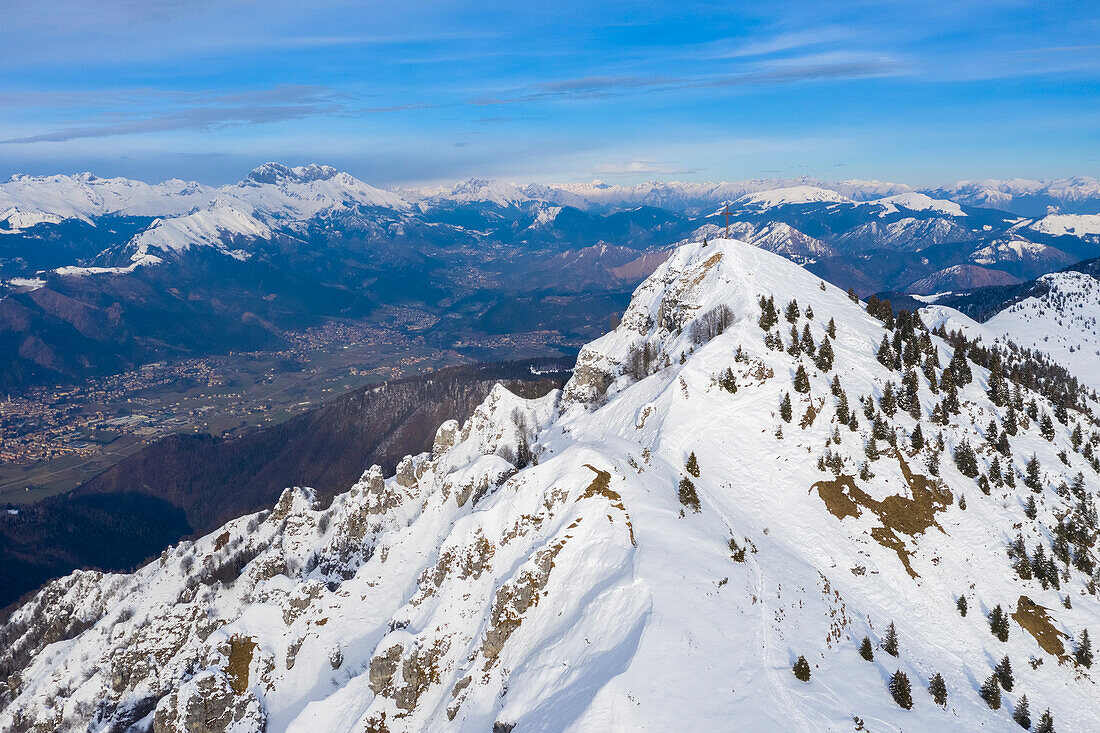 Aerial view of the iron cross on top of Pizzo Formico with Val Seriana and Presolana in the background in winter. Monte Farno, Gandino, Valgandino, Val Seriana, Bergamo province, Lombardy, Italy.
