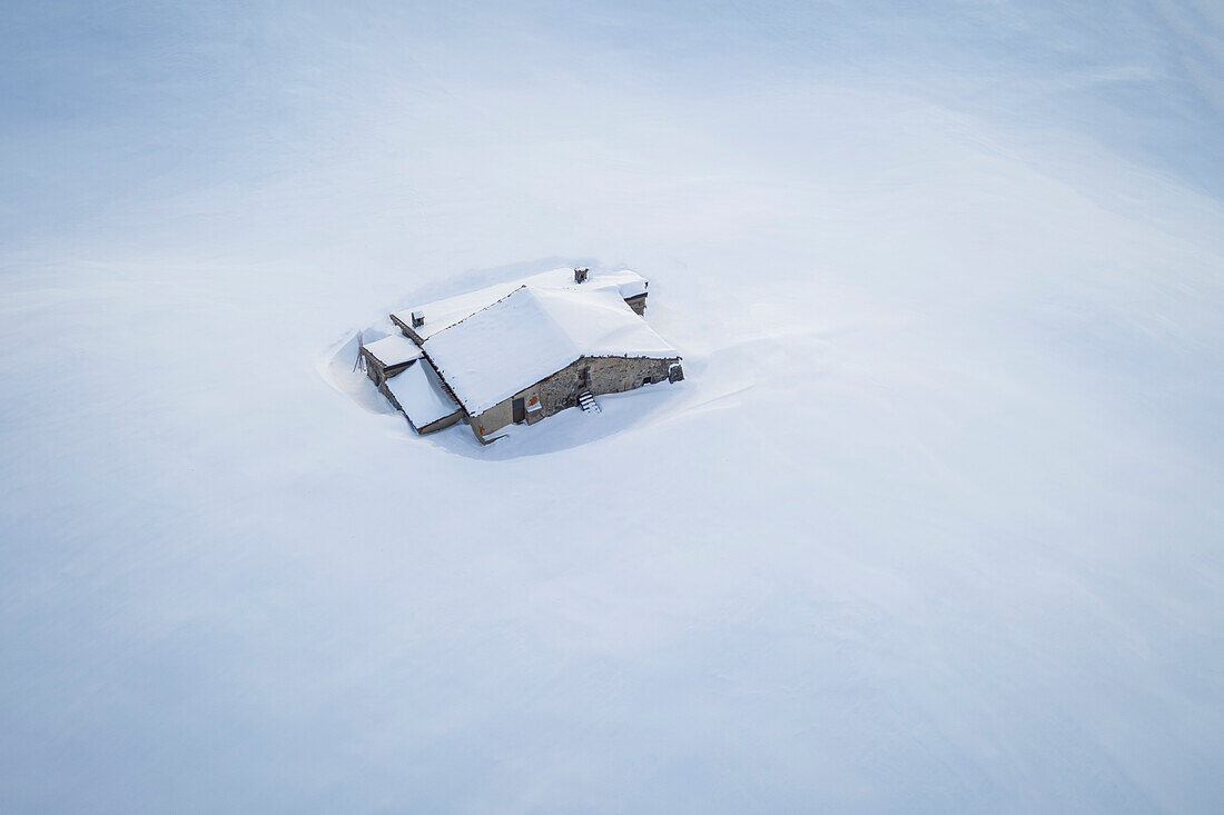 Aerial view of a mountain hut covered in snow at Monte Farno. Monte Farno, Gandino, Valgandino, Val Seriana, Bergamo province, Lombardy, Italy.