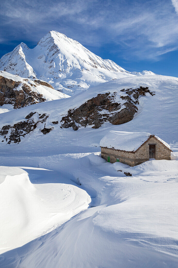 Blick auf eine Hütte in der Nähe der Maria-Luisa-Hütte und des Kastelhorns im Hochtal von Formazza im Winter. Riale, Formazza, Valle Formazza, Verbano Cusio Ossola, Piemont, Italien.