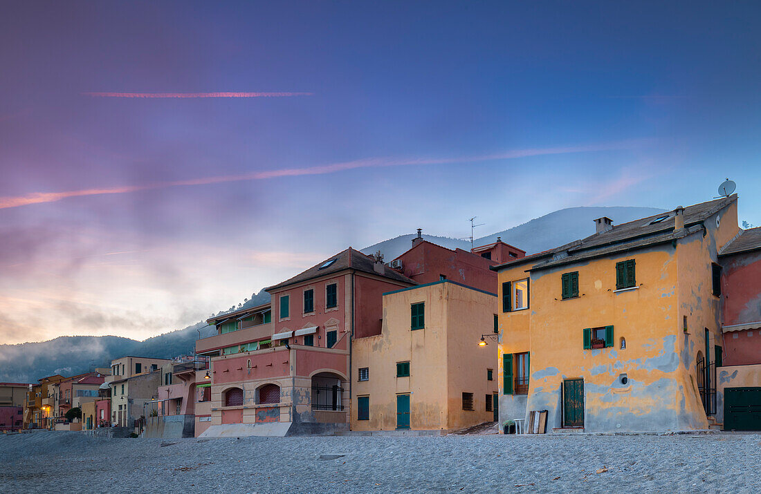 Nebliger Sonnenuntergang über den bunten Häusern und dem Strand von Varigotti, Finale Ligure, Bezirk Savona, Ponente Riviera, Ligurien, Italien.