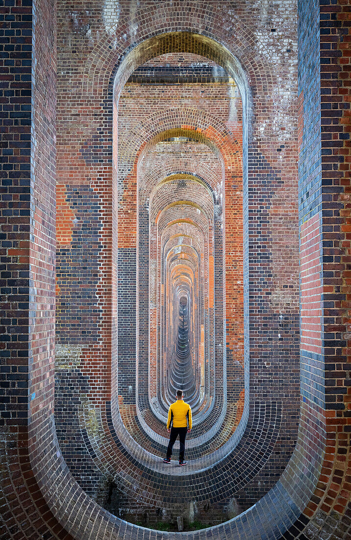 Eine Person starrt auf das Ouse-Viadukt aus dem darunter liegenden Gewölbe. Sussex, Südengland, Vereinigtes Königreich.