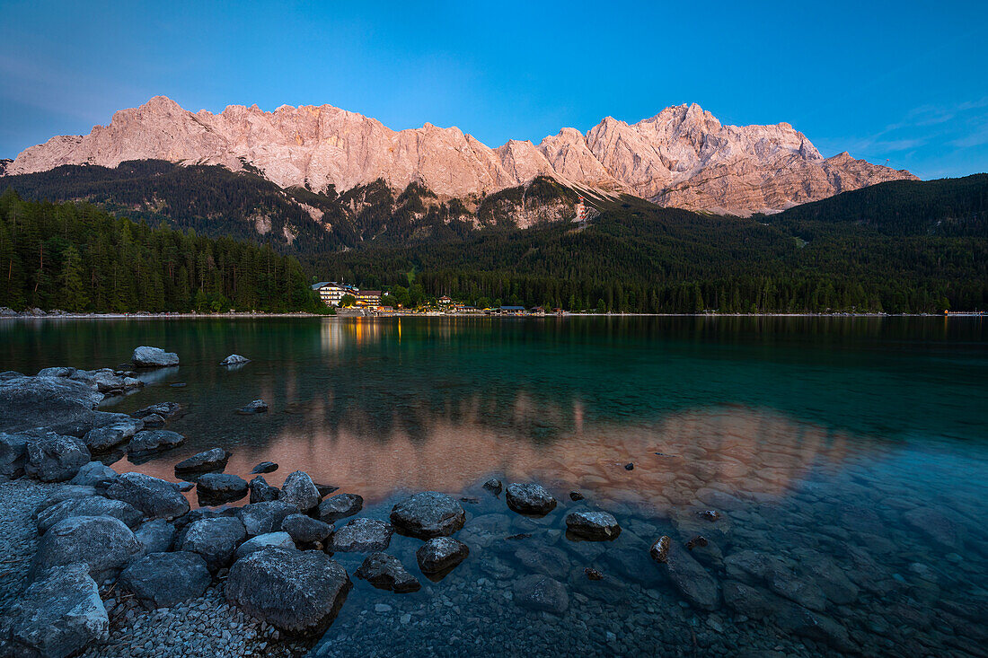 Eibsee und Zugspitze bei Sonnenuntergang im Sommer mit Blick auf das beleuchtete Eibsee Hotel, Garmisch Partenkirchen, Bayern, Deutschland, Deutschland, Westeuropa