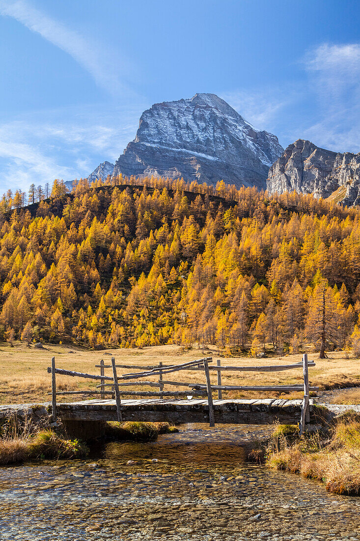 Herbstlicher Blick auf eine kleine Holzbrücke vor dem Monte Leone bei Piana del Veglia. Alpe Veglia, Cairasca-Tal, Divedro-Tal, Ossola-Tal, Varzo, Piemont, Italien.