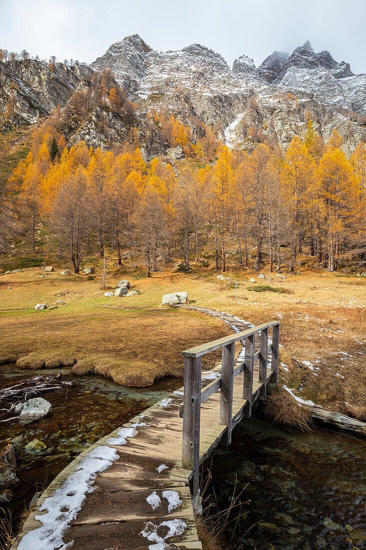 Autumnal view of the bridge over Lago delle Streghe lake at Crampiolo, Alpe Devero. Alpe Devero, Devero valley, Antigorio valley, Ossola valley, Piedmont, Verbano Cusio Ossola district, Italy.