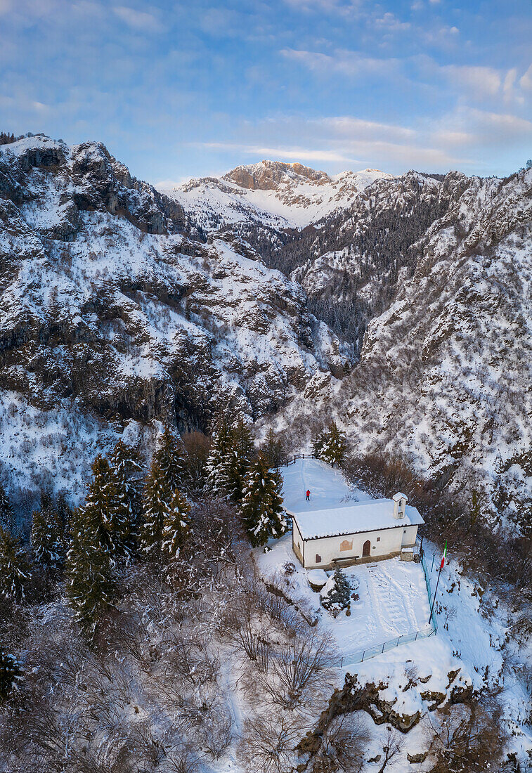 Luftaufnahme der kleinen Kirche San Peder und des Presolana-Passes während eines winterlichen Sonnenuntergangs. Rusio, Castione della Presolana, Val Seriana, Bezirk Bergamo, Lombardei, Italien.