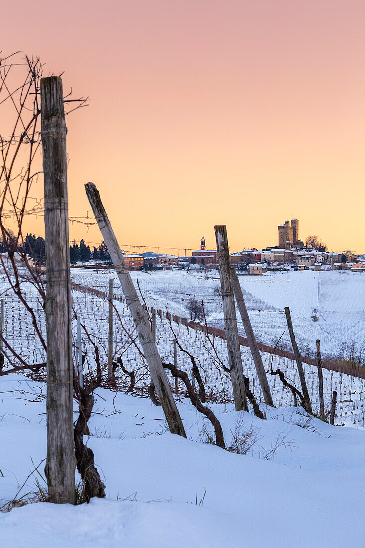 Winterlicher Sonnenuntergang über der mittelalterlichen Stadt Serralunga d'Alba und ihrer Burg, gesehen von den umliegenden Weinbergen. Serralunga d'Alba, Langhe, Piemont, Italien, Europa.