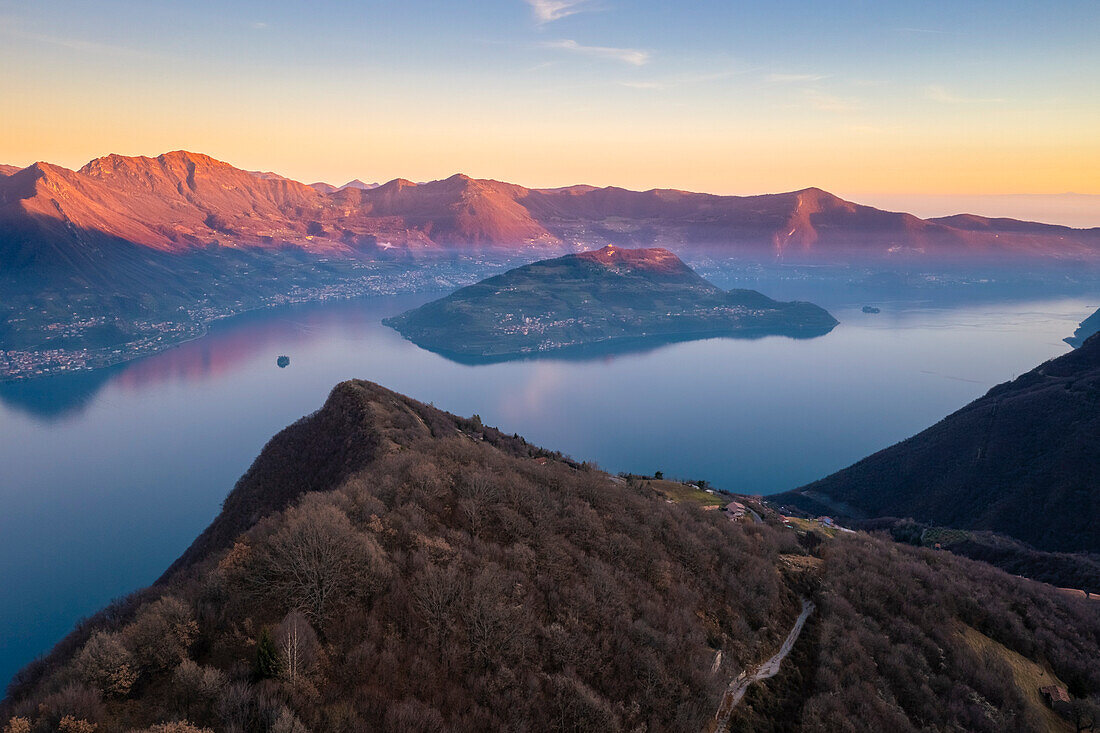 Aerial view of the top of a mountain dominating Lake Iseo at sunset with Montisola. Parzanica, Iseo Lake, Bergamo district, Lombardy, Italy.