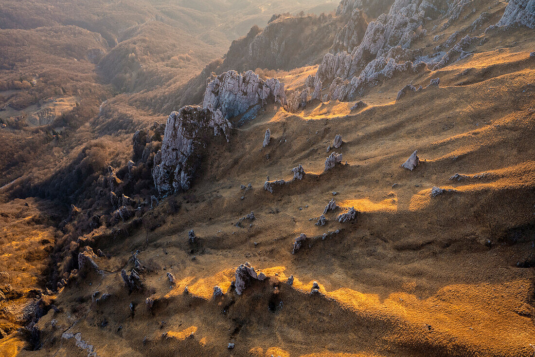 Aerial view of the side of Colle Pertusio and the valley below Rifugio Rosalba with it's rock formations at sunset. Piani Resinelli, Lecco, Lombardy, Italy.