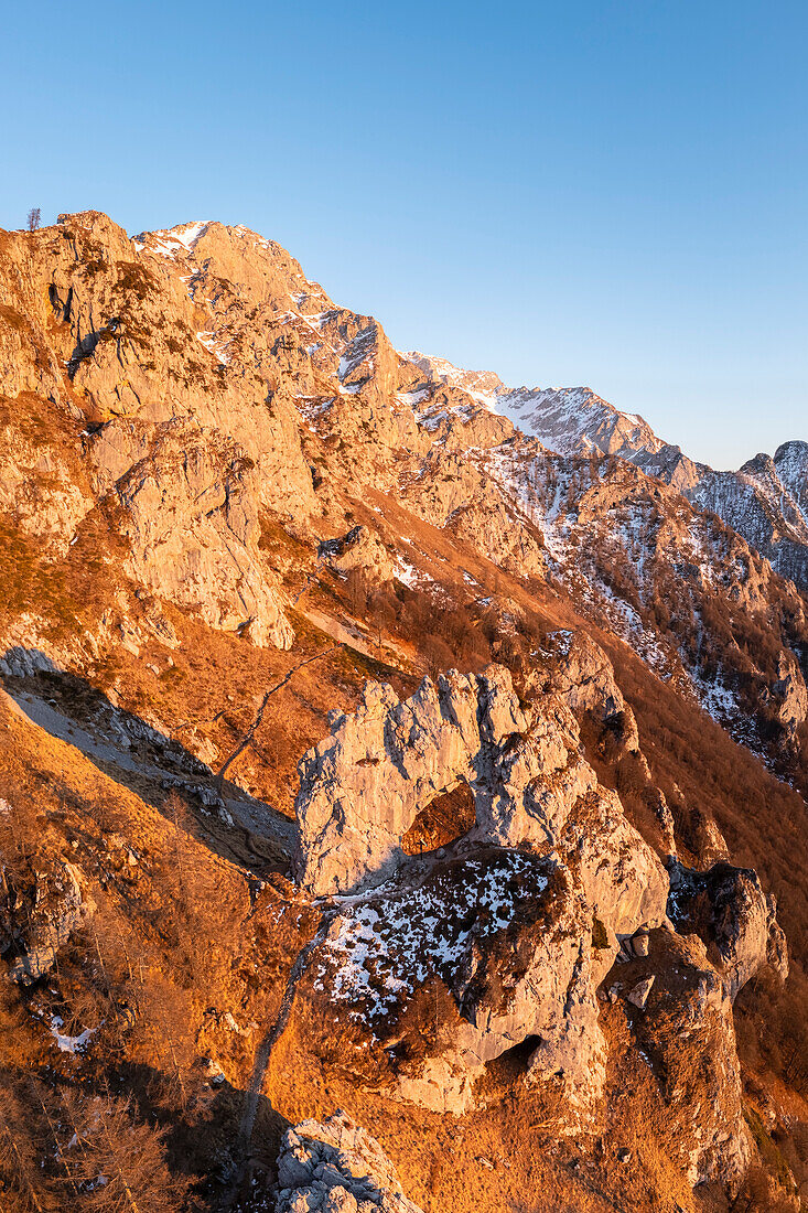 Aerial view of the natural rock arch called Porta di Prada with the Grigna Settentrionale mountain behind at sunset. Grigna Settentrionale(Grignone), Mandello del Lario, Lombardy, Italy.