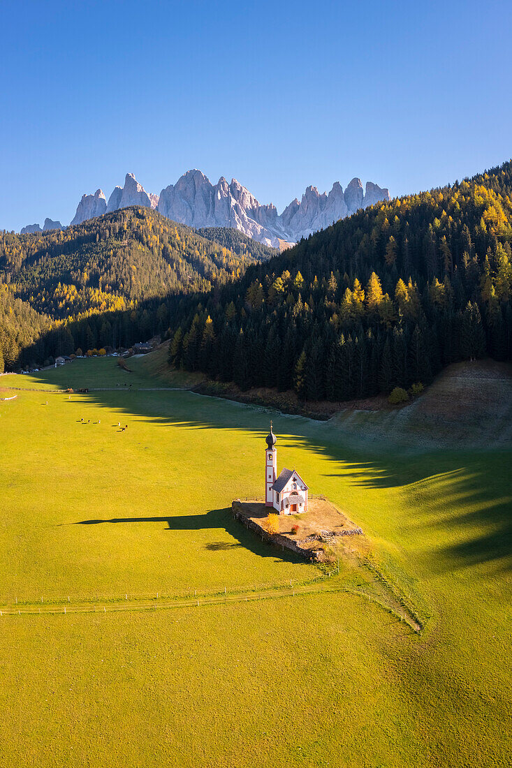 Luftaufnahme der Ranui-Kirche mit der Geislergruppe im Hintergrund. Santa Magdalena Val di Funes, Funes-Tal, Bozen, Südtirol, Trentino Südtirol, Italien.