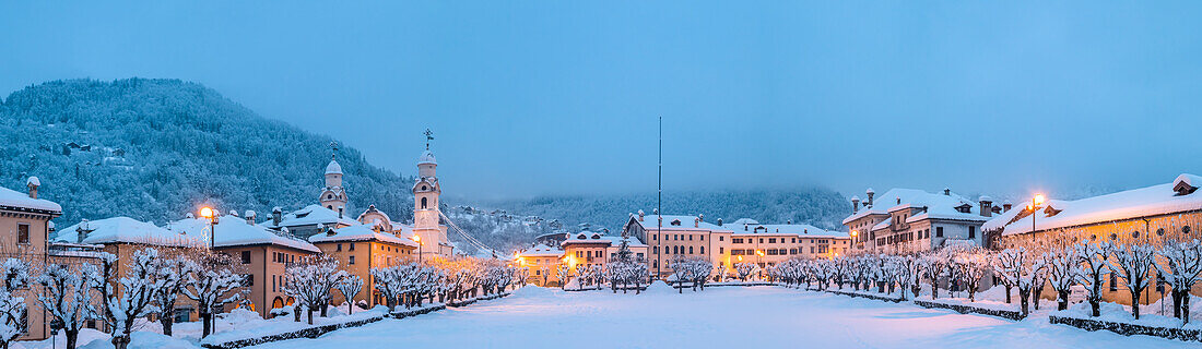 Europe, Italy, Veneto, Belluno province. The historic center of Agordo with the church and the snow-covered park of Broi