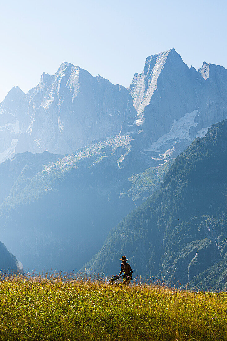 The man who cuts the grass with Badile Peak in background. Tombal, Soglio, Val Bregaglia, canton of Graubunden Switzerland