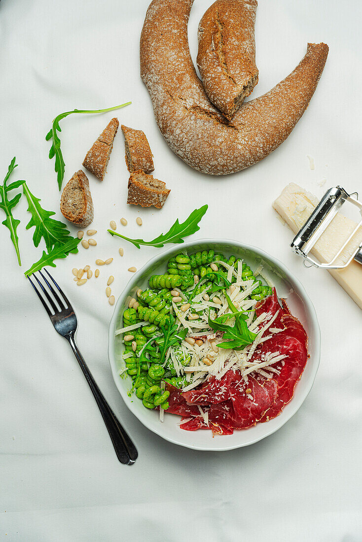 A tasty “bowl” with either hot or freshly drained pasta. Short pierced fusilli with rocket pesto, parmesan, pine nuts and bresaola dry-cured meat from Valtellina, Northern Italy