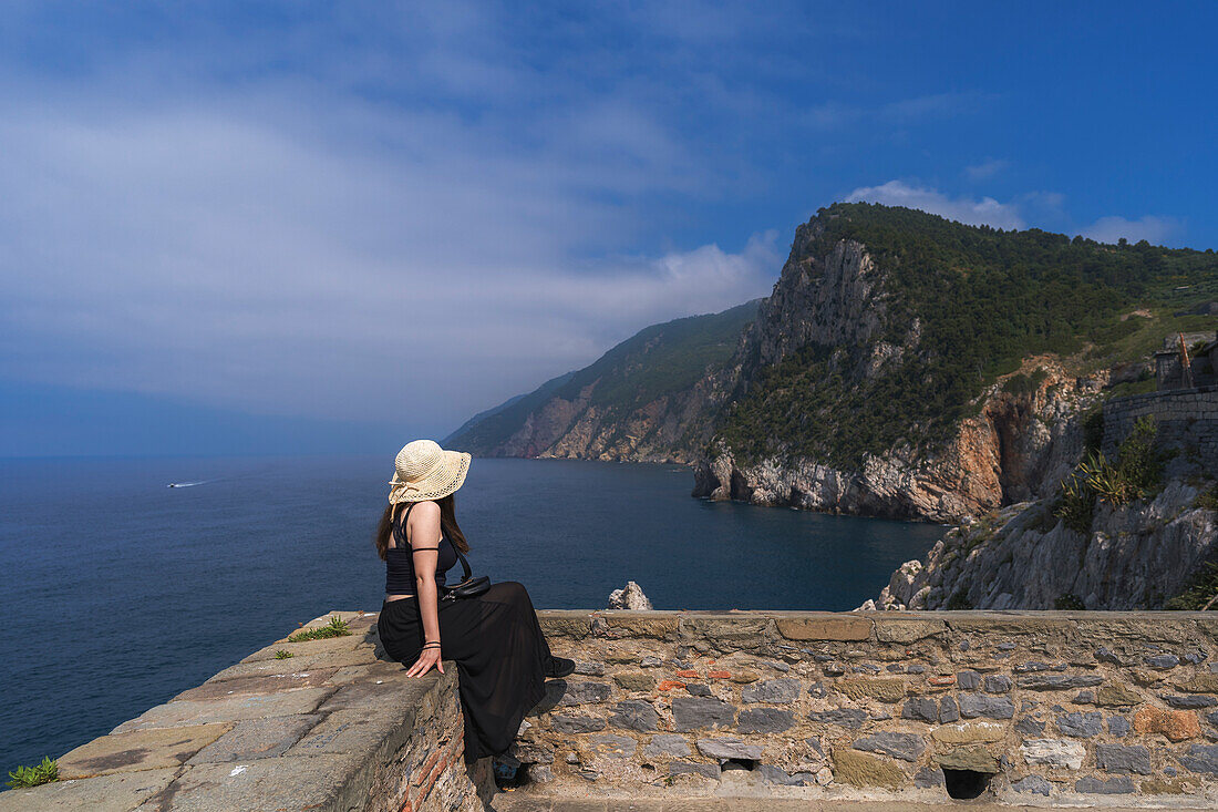 A young woman is admiring the landscape from the panoramic point near the San Pietro's church in Portovenere, La Spezia province, Liguria, Italy, Europe