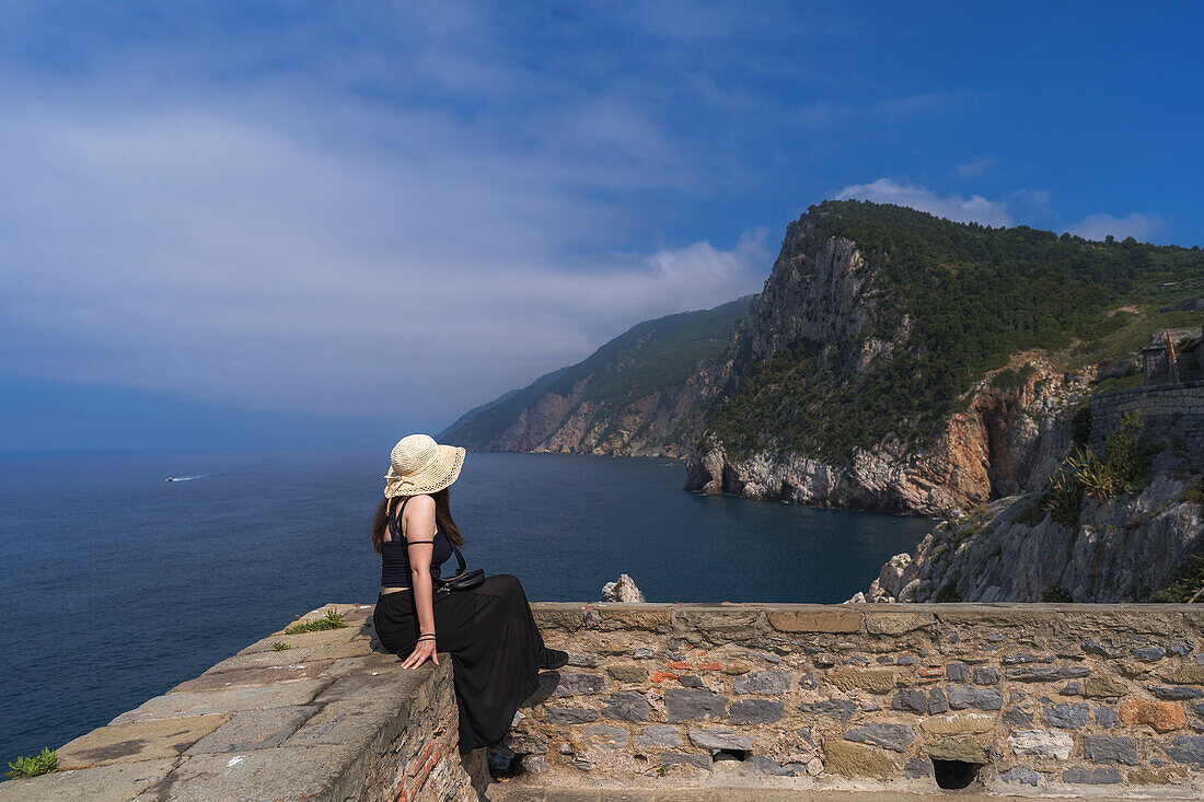 Eine junge Frau bewundert die Landschaft von einem Aussichtspunkt in der Nähe der Kirche San Pietro in Portovenere, Provinz La Spezia, Ligurien, Italien, Europa