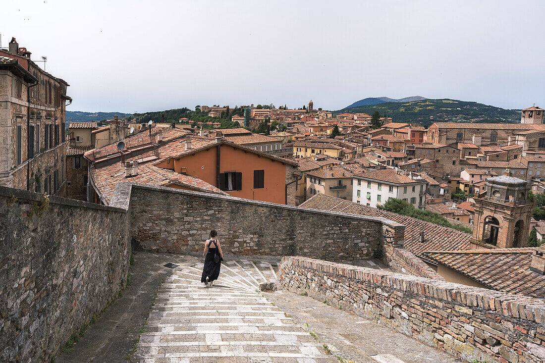 A young woman walking through "Porta Sole" in Perugia, Umbria, Italy, Europe.