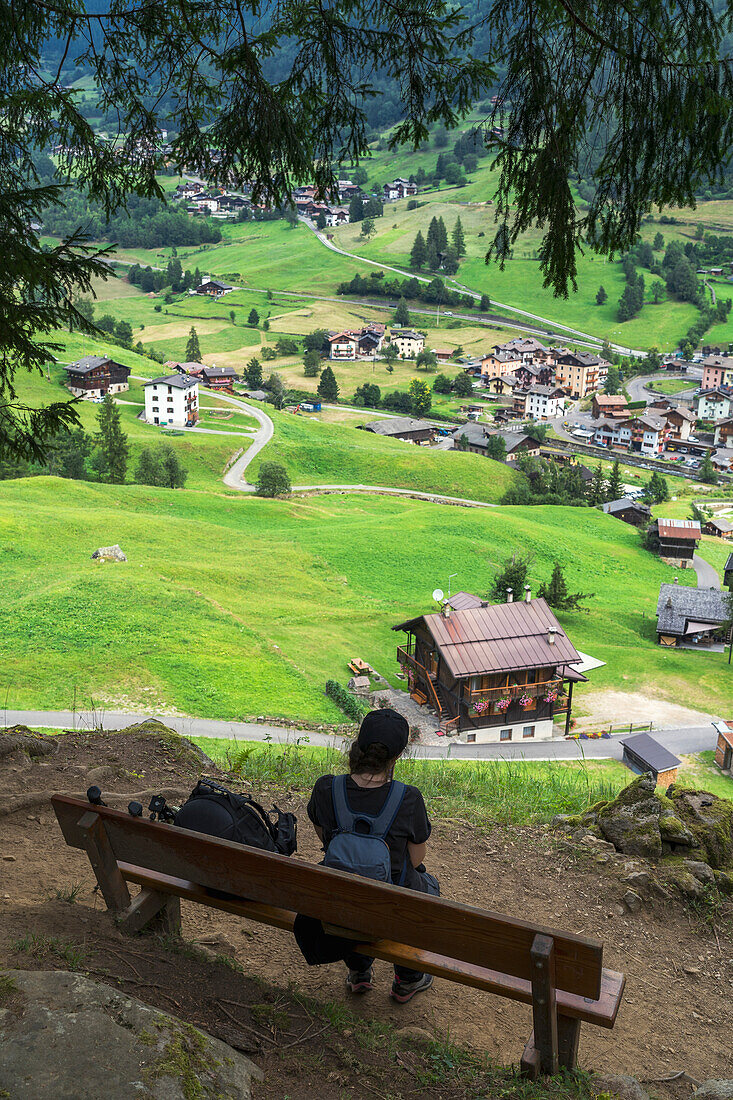 Ein junges Mädchen sitzt auf einer Bank am Wanderweg zu den Valorz-Wasserfällen, San Bernardo, Rabbi, Rabbital, Autonome Provinz Trient, Trentino Alto-Adige/Südtirol, Italien
