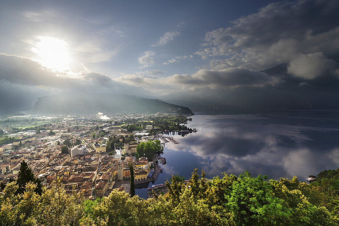 Riva del Garda bei Sonnenaufgang, Panoramafoto von Bastione mit Spiegelungen des Himmels und der Wolken im See Riva del Garda, Trentino Alto Adige, Provinz Trento, Norditalien, Südeuropa