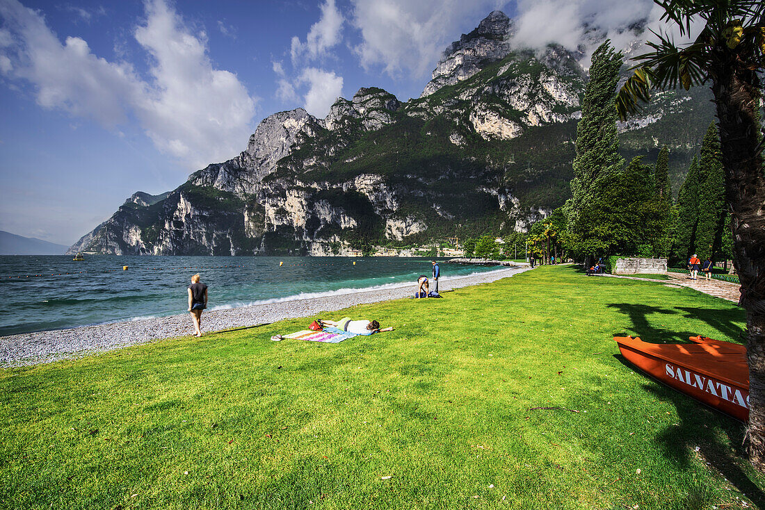 Sabbioni Strand in Riva del Garda, mit Touristen, Gardasee und Berg im Hintergrund Riva del Garda, Trentino alto adige, Provinz Trento, Norditalien, Südeuropa