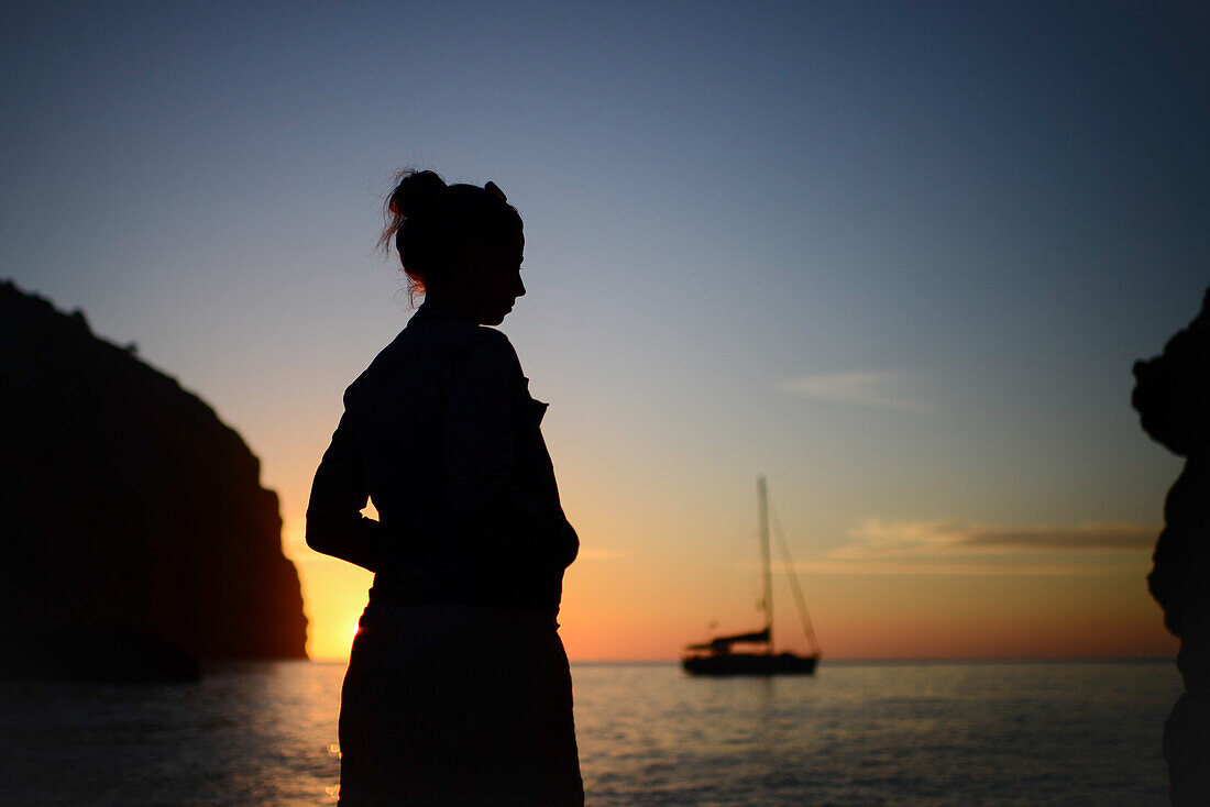 Silhouette einer jungen Frau, die den Sonnenuntergang an einem schönen Strand genießt