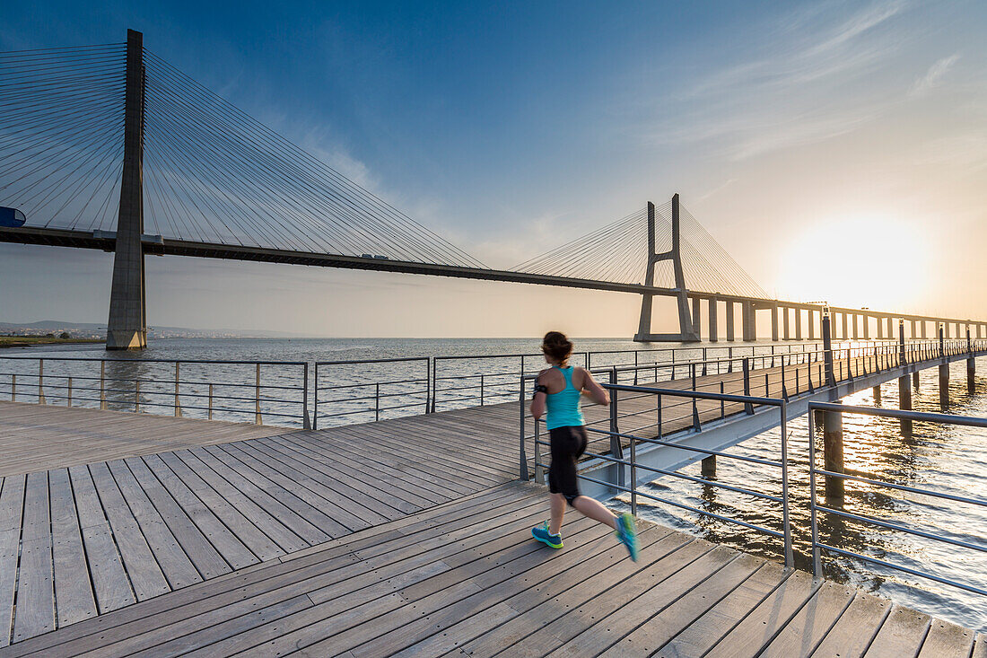 Morgenlauf in der Nähe der Vasco-Da-Gama-Brücke bei Sonnenaufgang, Lissabon, Portugal