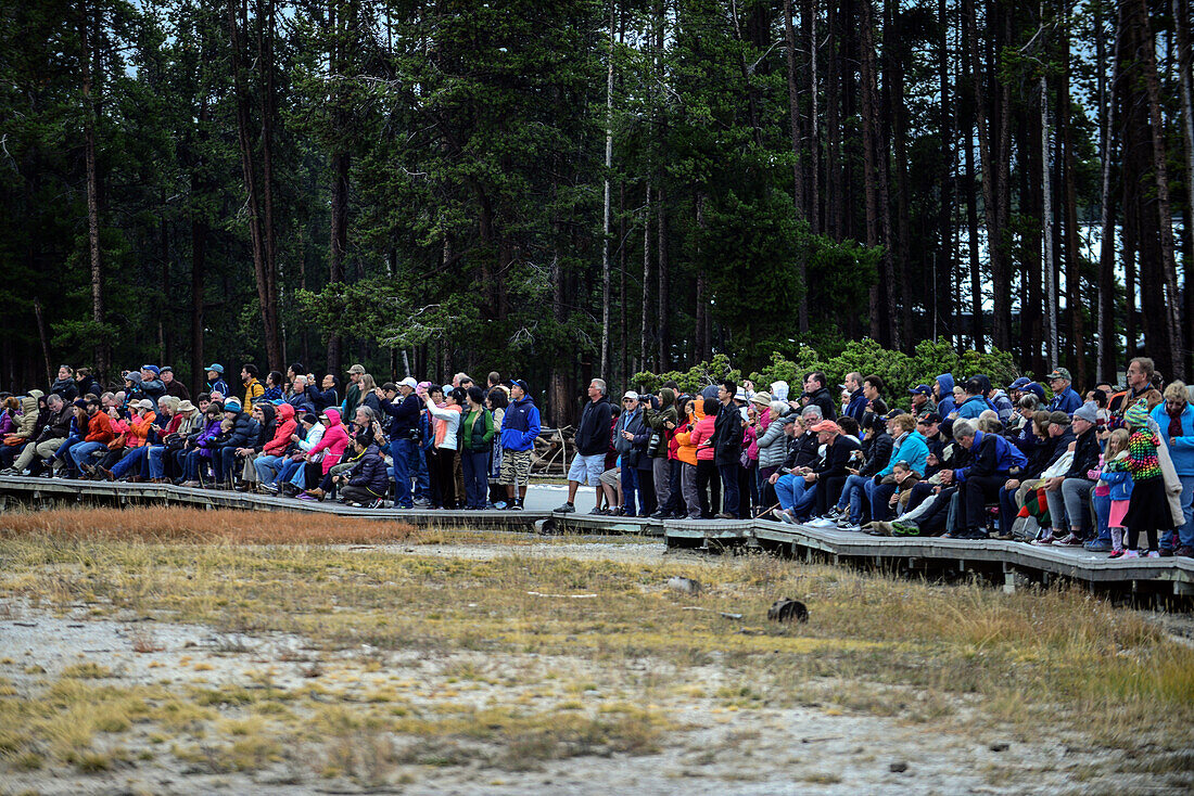 Visitors watch Old Faithful geyser´s eruption in Upper Geyser Basin, Yellowstone National Park, USA