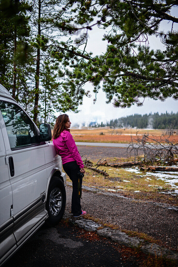 Young woman stands by camper van in Yellowstone National Park, USA