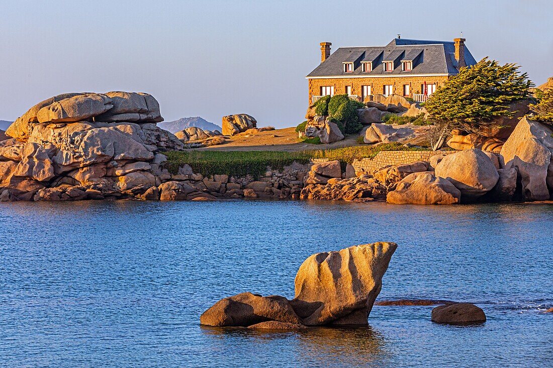 Haus auf den Felsen bei Sonnenuntergang, Kieselstrand von Toul Drez, renote island point, tregastel, rosa Granitküste, cotes-d'armor, Bretagne, Frankreich