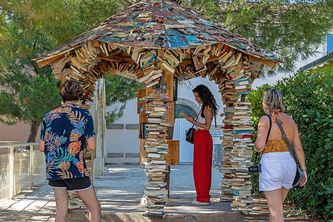 Vorbeigehender Leser vor einem Kiosk für gebrauchte Bücher, Tauschkiosk mit Büchern, aniane, herault, occitanie, frankreich