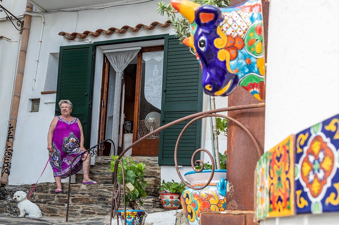 Anwohnerin mit ihrem Hund vor dem mit Mosaiken verzierten Haus, Dorf, in dem Salvador Dalí lebte, Cadaques, Costa Brava, Katalonien, Spanien