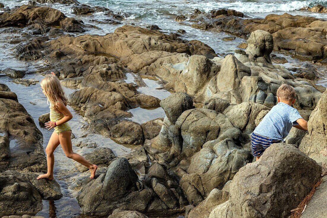 Kinder spielen auf den Felsen in der Nähe des Hafens von Poussai, cap esterel, saint-raphael, var, frankreich