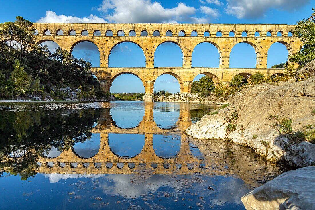 The three-leveled pont du gard, old roman aqueduct that crosses the gardon river and dates from the first century bc, listed as a historic monument, vers-pont-du-gard, france