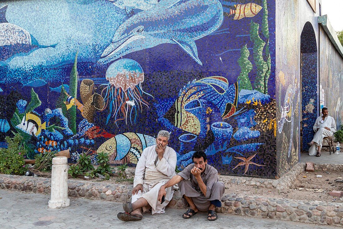 Cigarette break in front of the entrance to the mosaic-covered souk, el dahar market, popular quarter in the old city, hurghada, egypt, africa