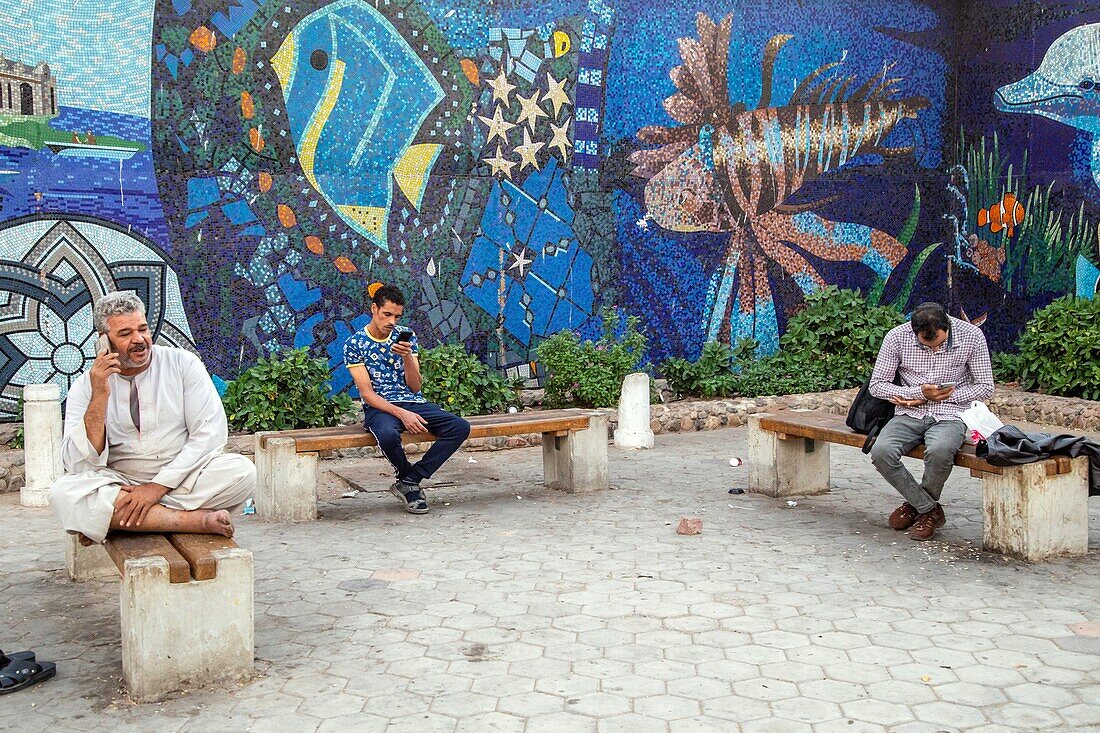 Men with their cell phones in front of the entrance to the mosaic-covered souk, el dahar market, popular quarter in the old city, hurghada, egypt, africa