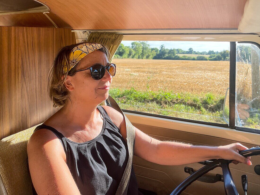 Woman at the steering wheel for a drive in the countryside in a volkswagen combi, manche, normandy, france