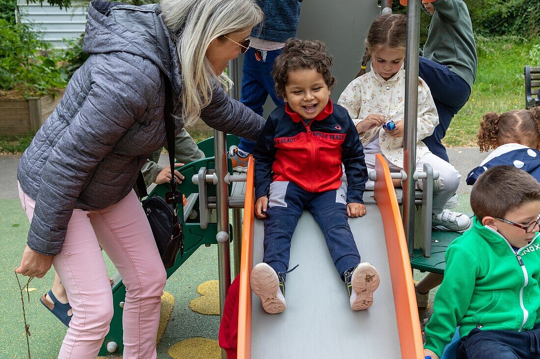 On the slide with friends, relaxation and games in the playground, integration of children with difficulties in the public schools, slight mental disabilities, roger salengro kindergarten, louviers, eure, normandy, france