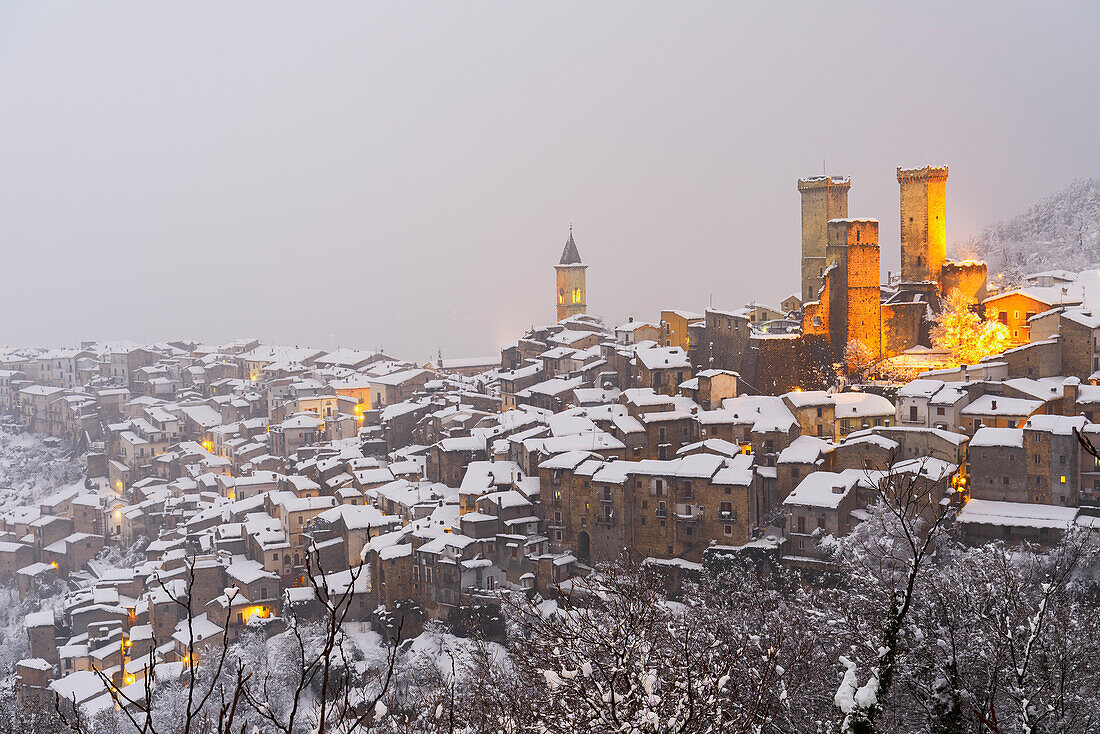 Das winterliche Panorama des beleuchteten mittelalterlichen Dorfes Pacentro mit dem Schloss, dem Glockenturm und dem schneebedeckten Haus, Gemeinde Pacentro, Nationalpark Maiella, Provinz L'aquila, Italien