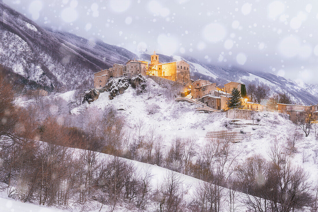 Schneefall im beleuchteten Bergdorf Roccacaramanico, Maiella-Nationalpark, Provinz Pescara, Abruzzen, Italien