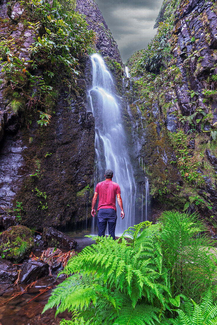 Mann vor dem malerischen Wasserfall Ribeira do Fundao, Gemeinde Lajes das Flores, Insel Flores (Ilha das Flores), Azoren-Archipel, Portugal, Europa