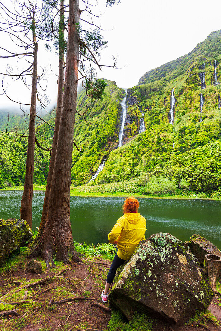 Woman sits and admires the waterfall of Ribeira do Ferreiro, Poco Ribeira do Ferreiro (Alagoinha), Lajes das Flores municipality, Flores Island (Ilha das Flores), Azores archipelago, Portugal, Europe