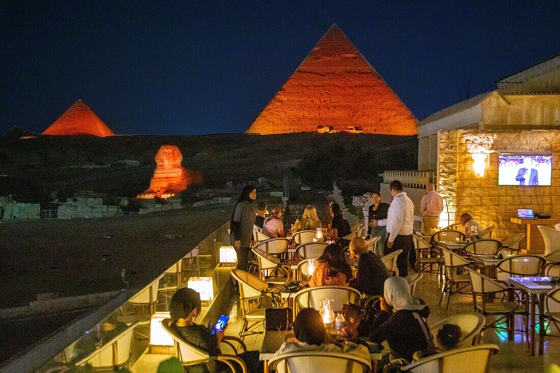 Außencafé bei Einbruch der Dunkelheit für die Ton- und Lichtshow auf den Pyramiden und der Sphinx von Gizeh, Kairo, Ägypten, Afrika
