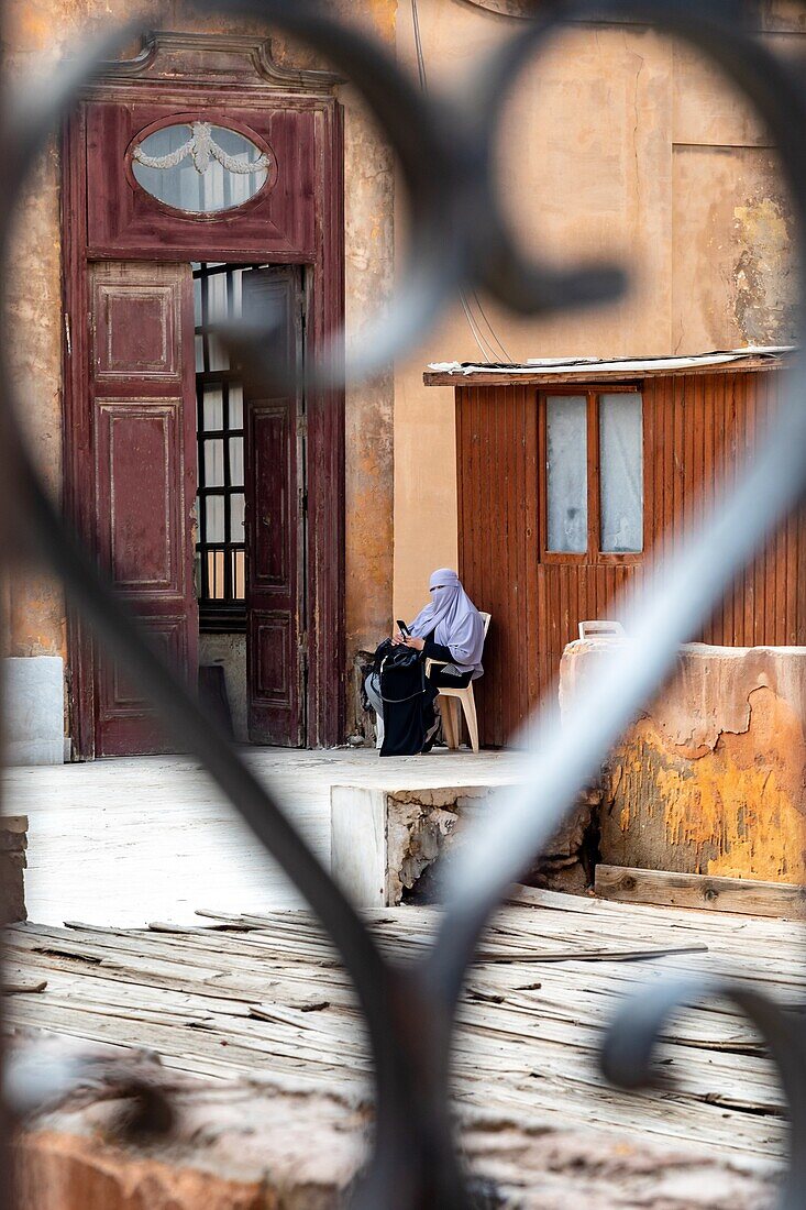 Veiled woman with her cell phone in the saladin citadel, salah el din, built in the 12th century, cairo, egypt, africa