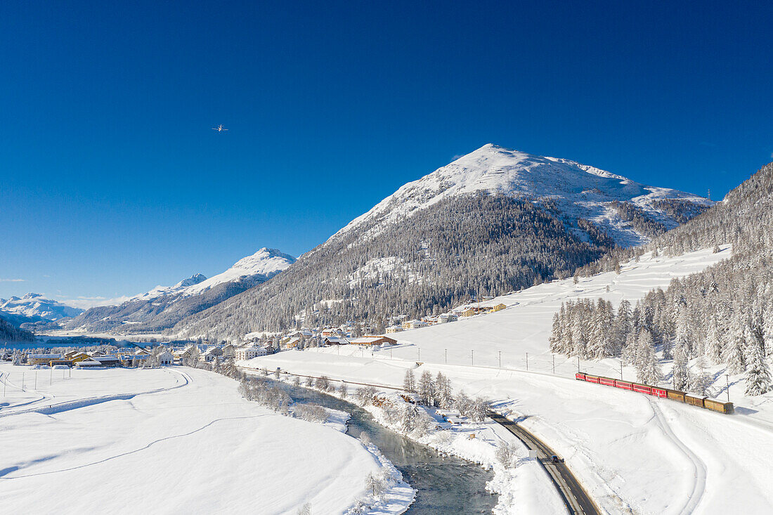Klarer Himmel auf Bernina Express Zug im Schnee am Ufer des Inns, Madulain, Kanton Graubünden, Engadin, Schweiz