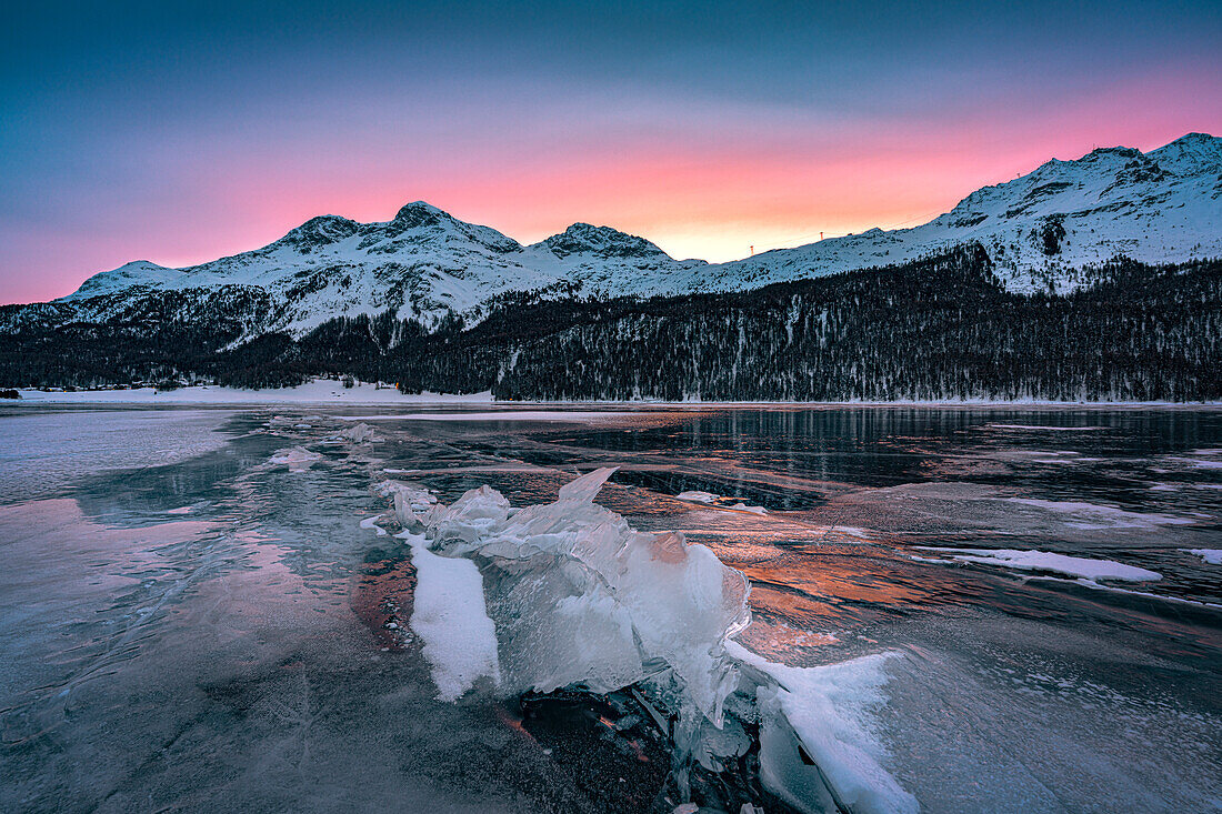 Eisblöcke auf dem zugefrorenen Silvaplanasee, eingerahmt von schneebedeckten Bergen in der Morgendämmerung, Maloja, Engadin, Kanton Graubünden, Schweiz