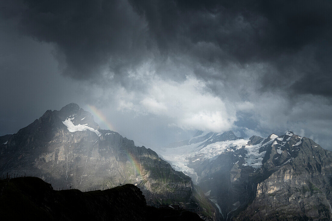 Storm clouds over Wetterhorn and Schreckhorn mountains lit by rainbow, Grindelwald, Bernese Alps, Canton of Bern, Switzerland
