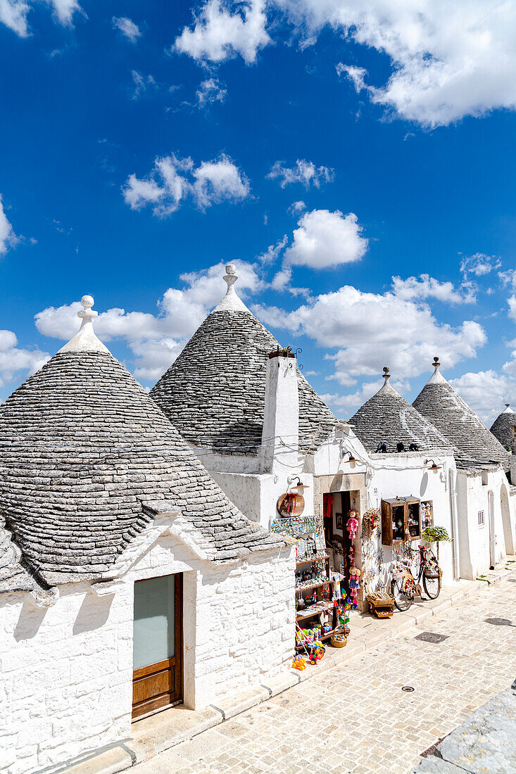 Strahlender Sonnentag über Trulli-Häusern in der alten Gasse von Alberobello, Provinz Bari, Apulien, Italien